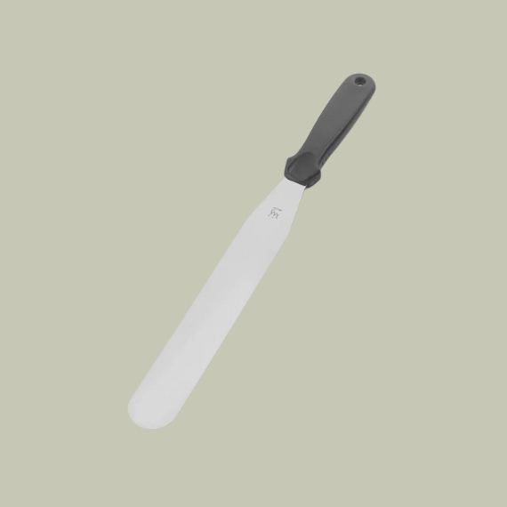 A stainless steel palette knife with a black handle positioned obliquely against a pale green background.
