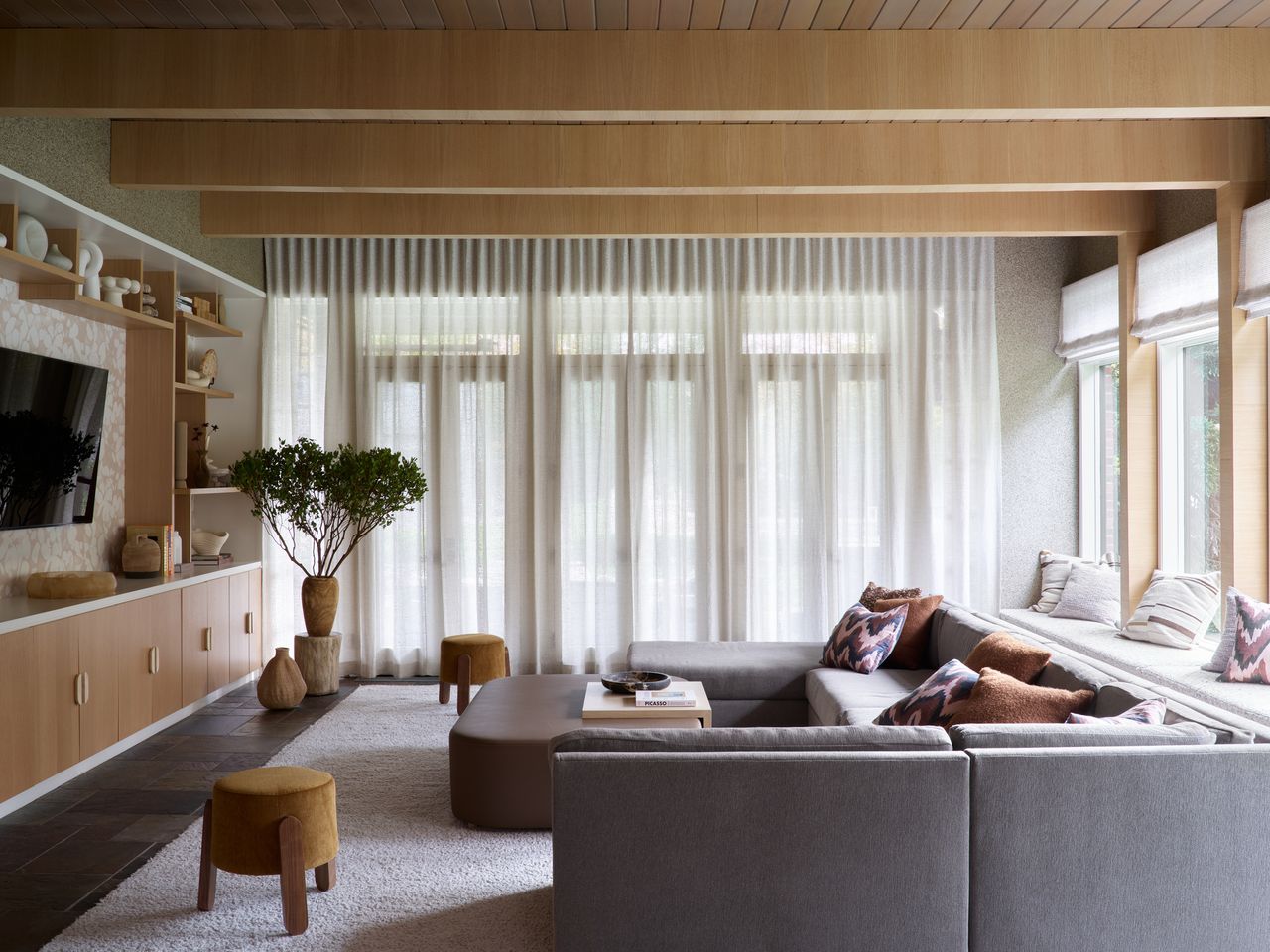 living room with a large grey couch and wooden built-in shelving