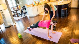 PT adjusts form of woman holding the plank position