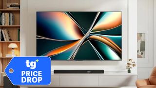 The Hisense U65QF, wall-mounted in a modern living space next to a superimposed, blue-colored tag that reads: "TG Price Drop"