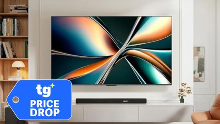 The Hisense U65QF, wall-mounted in a modern living space next to a superimposed, blue-colored tag that reads: "TG Price Drop"