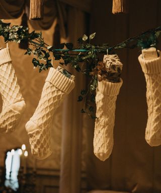 White knitted stockings hanging over a mantle stuffed with gifts