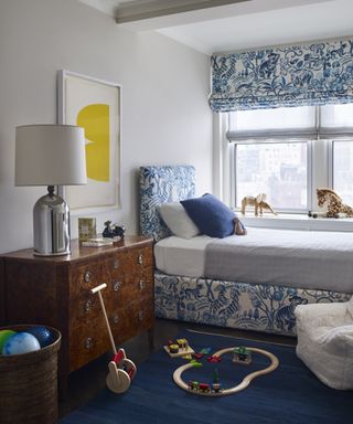 A child's bedroom with porcelain-inspired blue and white upholstered bed frame and blinds