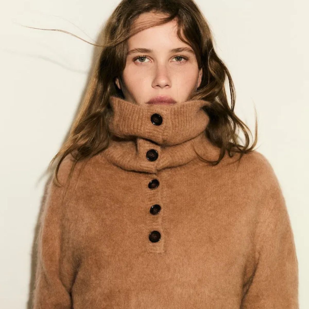 Model wearing a high-neck beige knit with buttons.