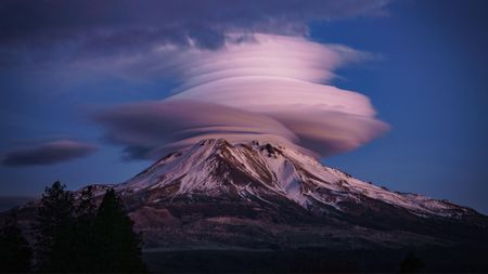 Wispy clouds in disk formation above volcano. 