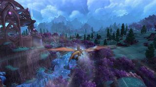 WoW 10.2.5 update - a player is dragonriding over a landscape with green fields and purple-leaved trees