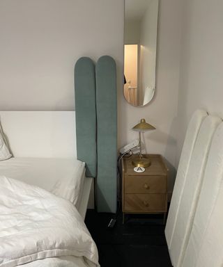 DIY upholstered scalloped headboard panels attached together in bedroom with oval oblong mirror and side table