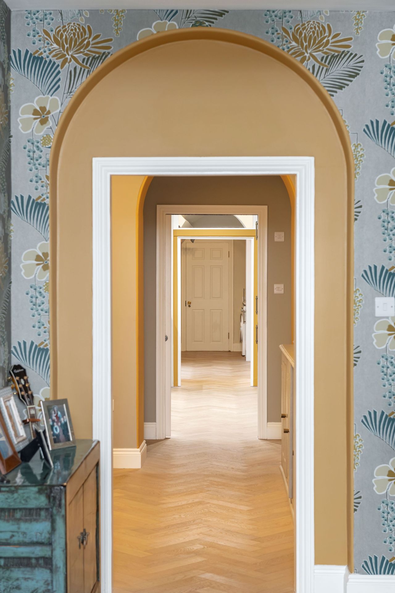 An arched doorway with wallpaper on one side and painted inside