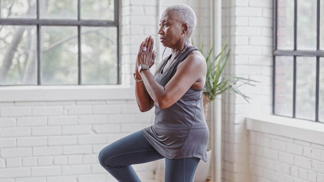 Woman balancing on one leg at home