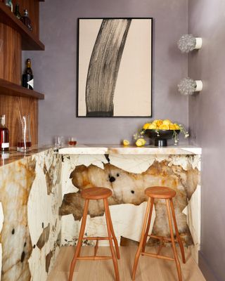 Corner of a bar area with marbled cladding, two bar stools and a framed artwork