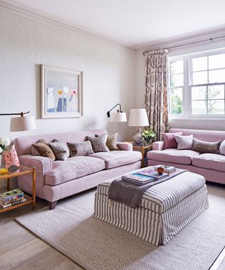 A living room with matching sofas, a striped footstool and cushions.