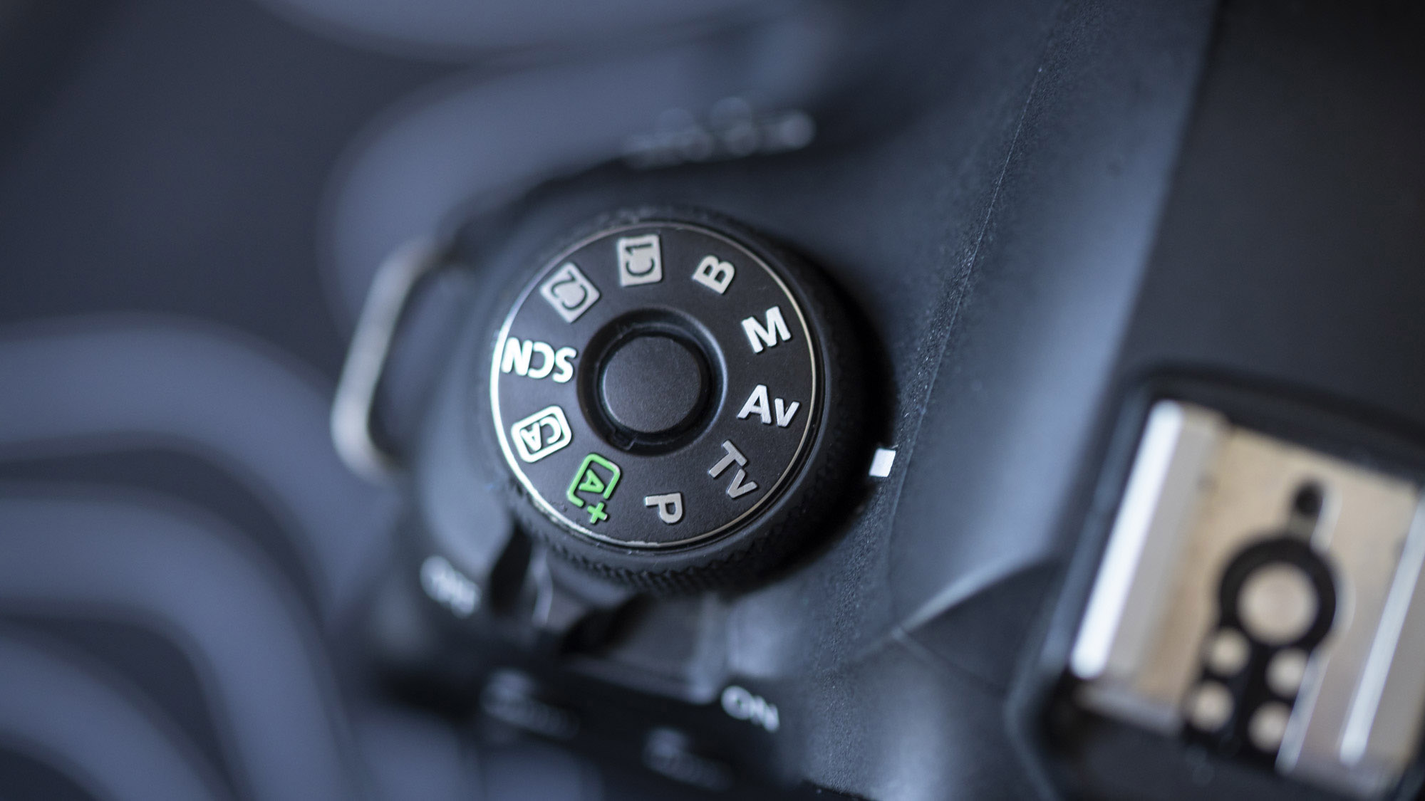 A close-up of the top of a Canon EOS 6D Mark II showing its Mode Dial with central locking button