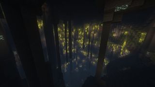 The inside of a hollow mountain in Minecraft, dotted with yellow lights and stone columns