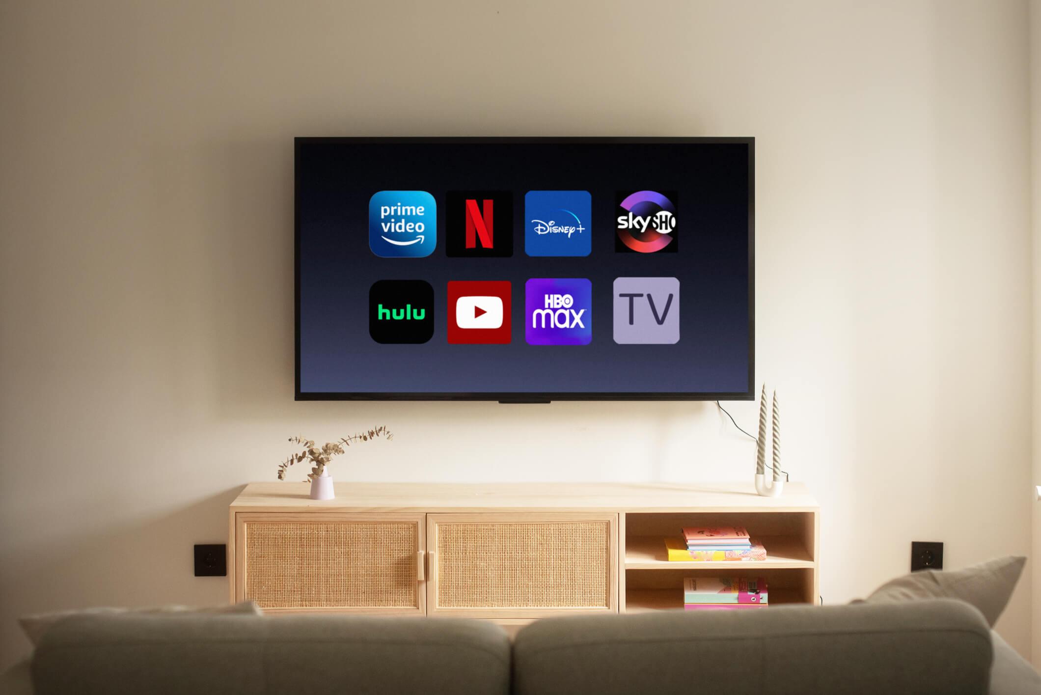  A smart TV displaying icons like Netflix and YouTube on the wall in a furnished home. 