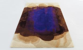 Wool rug with overlapping layers of cream, brown and purple colours