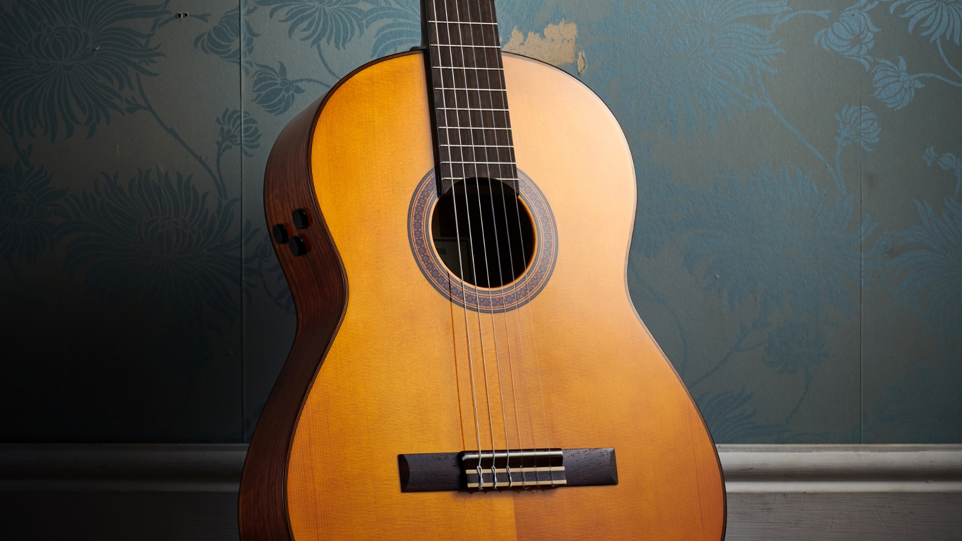 A Yamaha TransAcoustic acoustic guitar leaning against a wall
