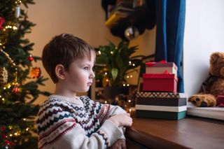 Little boy looking thoughtfully into window on Christmas holidays