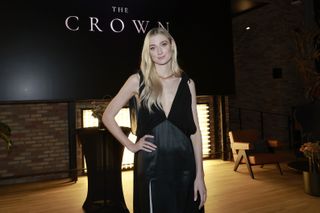 Elizabeth Debicki attending an event to promote "The Crown" in a black gown, posing with her hand on her hip