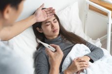 A woman sick in bed with a fever. 