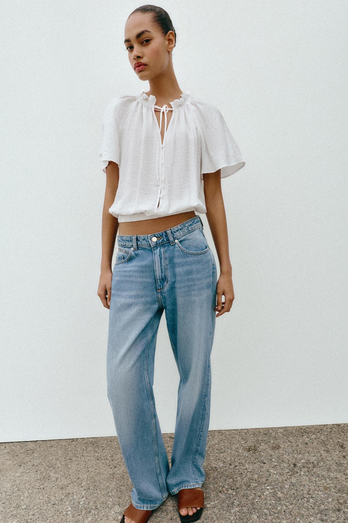 Model wears white blouse, blue jeans and brown sandals