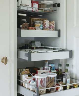 Pull out drawers in a white kitchen cabinet with food stored by IKEA