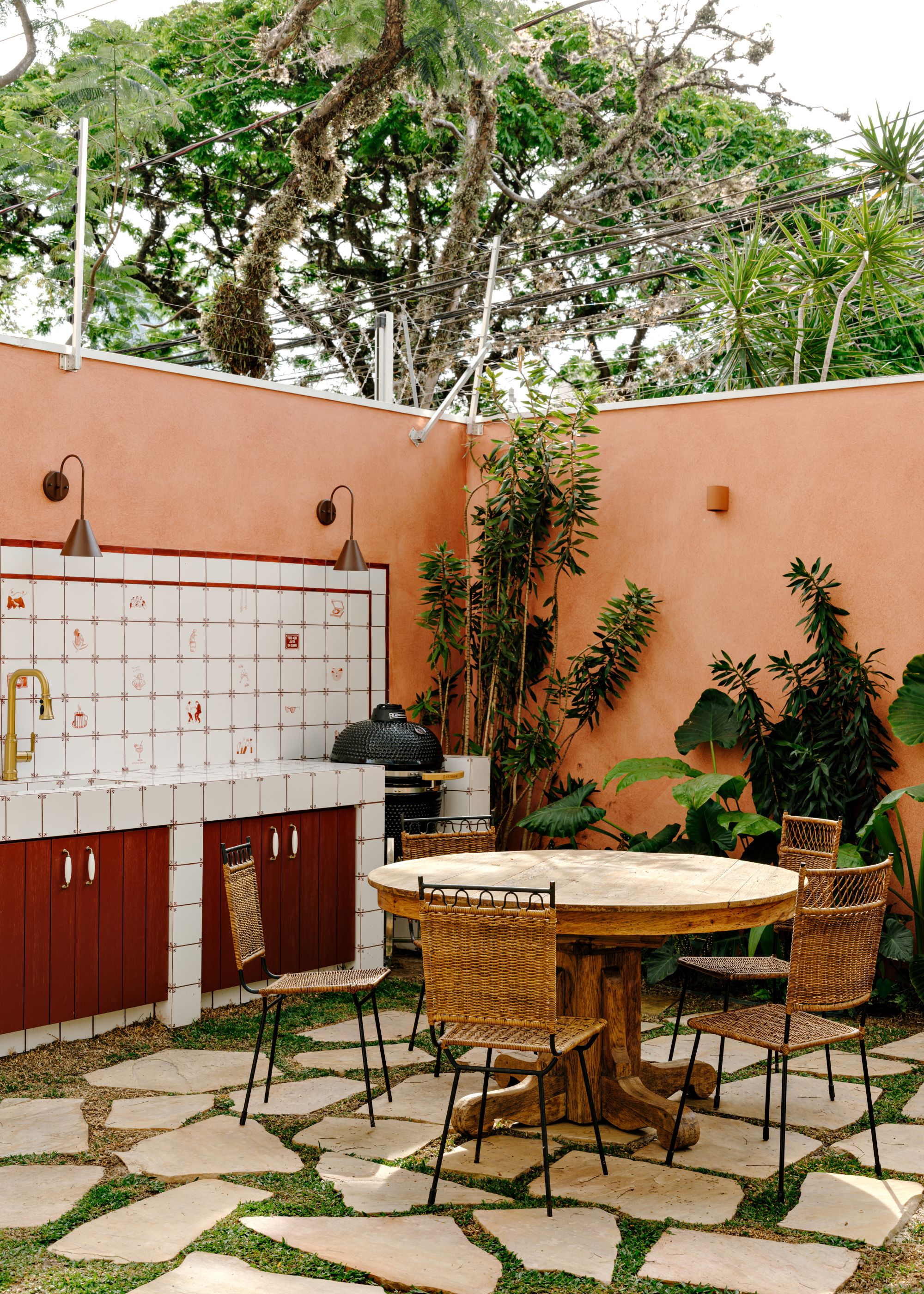 An outdoor space with landscaped garden, tiled floor, a small seating area and a sink