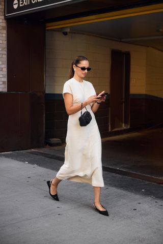 Woman wearing white midi dress and black accessories at New york Fashion Week