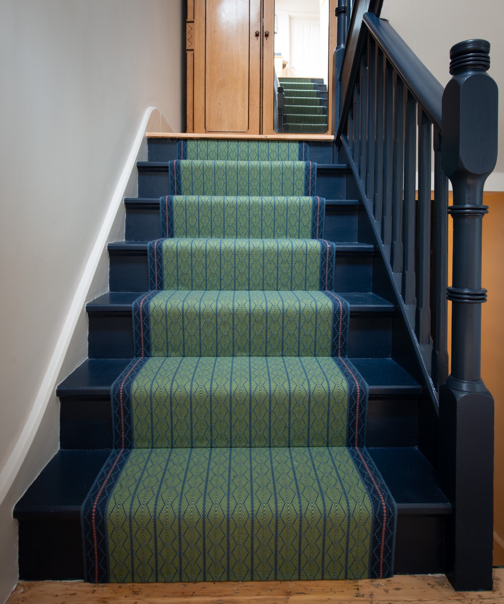 dark blue painted staircase with green and blue runner