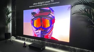 Hisense L9Q projector beaming image of masked face on screen