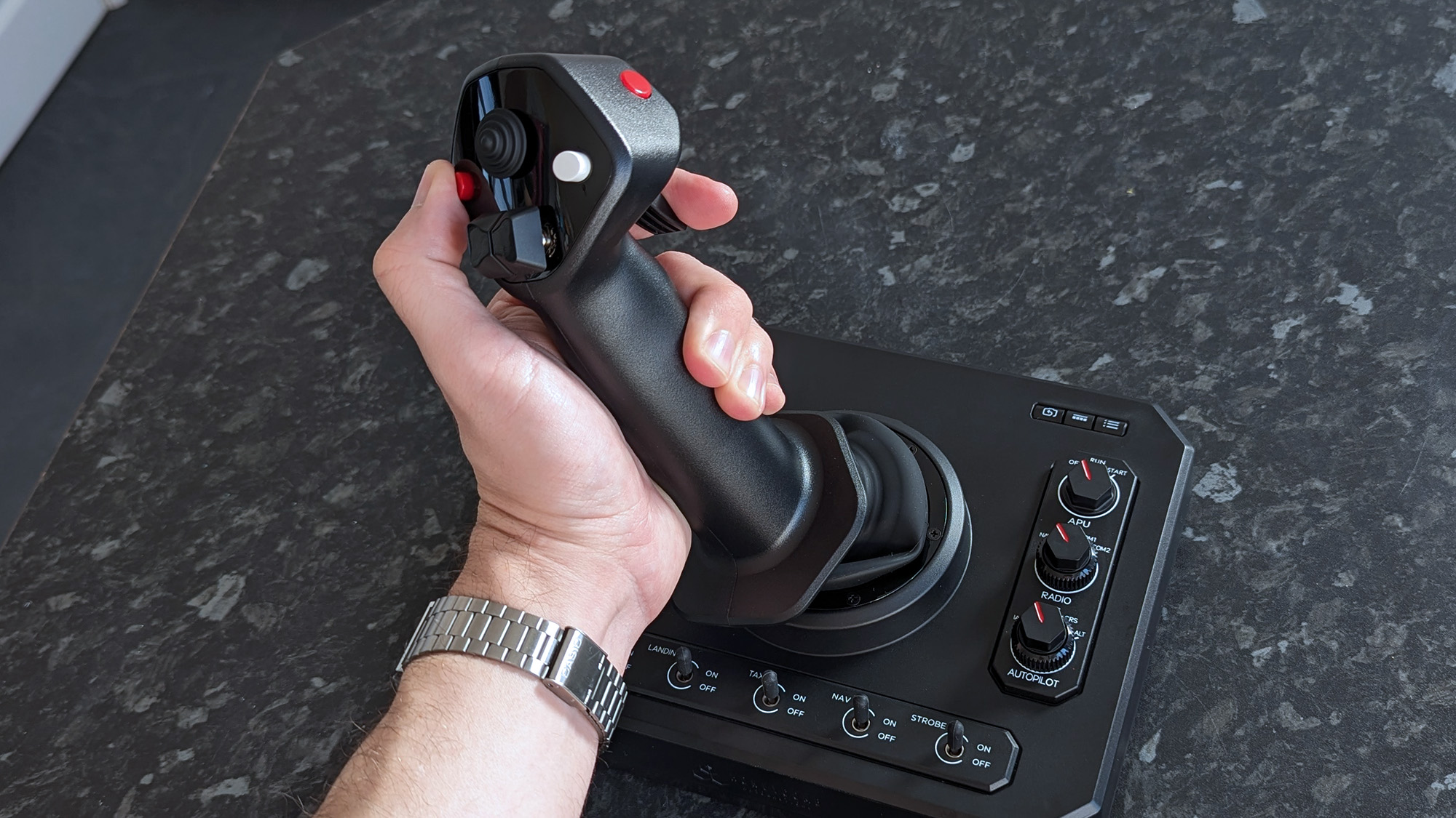 A hand grasping a Honeycomb Aeronautical Foxtrot Aviation Stick, placed on a marble-patterned countertop
