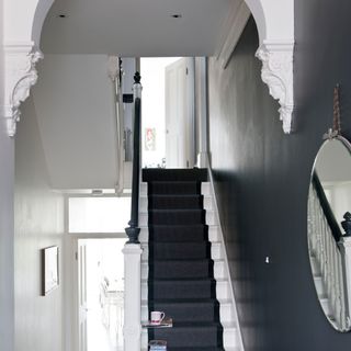White hallway with dark grey feature wall with round mirror