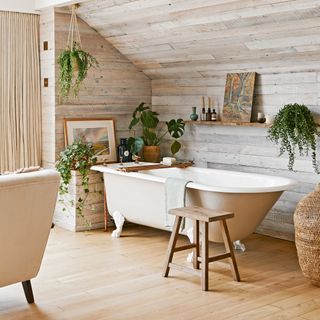 bathroom area in a bedroom with vaulted ceilings covered in wood panelling with a claw-footed freestanding bath