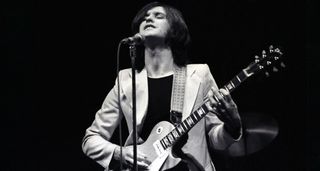 A black-and-white image of Dave Davies of the Kinks performing with a Goldtop Les Paul in 1974