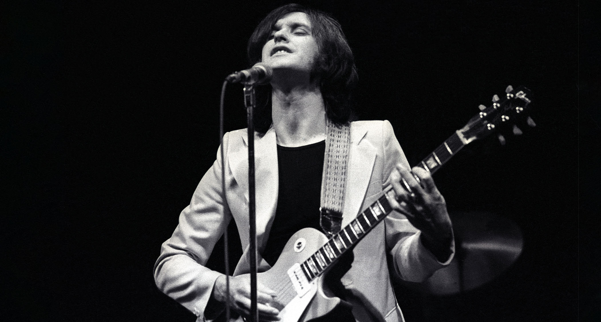 A black-and-white image of Dave Davies of the Kinks performing with a Goldtop Les Paul in 1974
