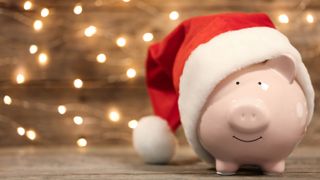 Pink piggy bank wearing a santa hat with fairy lights in background