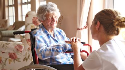 picture of elderly woman in wheelchair talking to nurse in long-term care facility