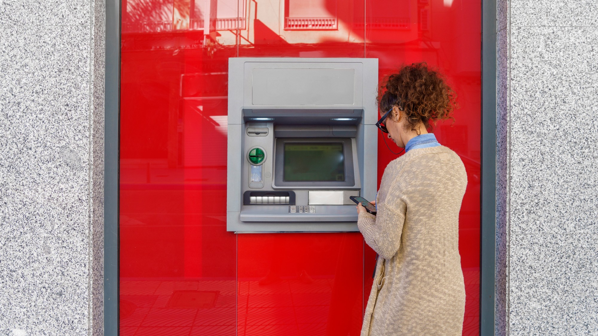 Rear view of woman using an ATM