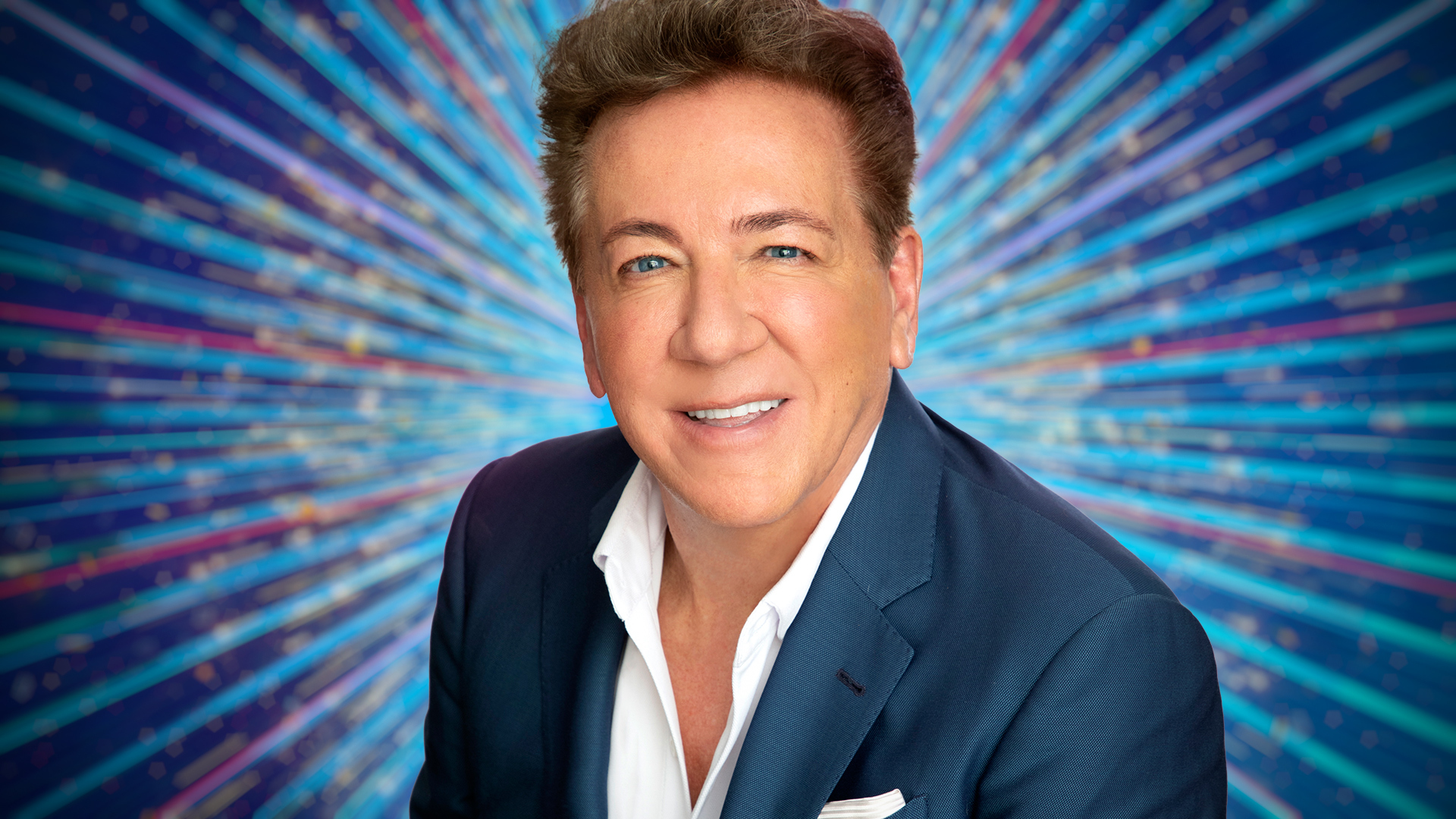 Ross King sitting with a blue sparkly background behind him.