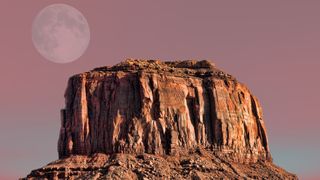 the moon can be seen in the sunset sky over monument valley in arizona