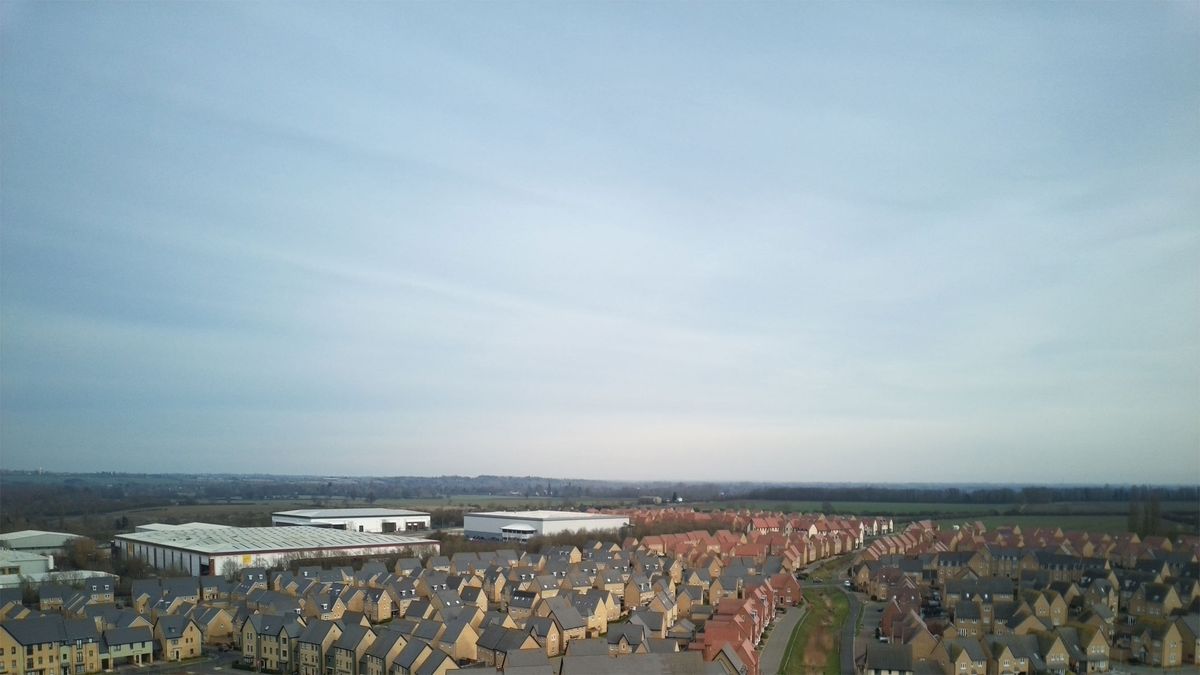 Aerial shots taken with the Veeniix V11PRO drone's camera showing houses and a skyline, roads with green surroundings and a multi-colored art display.