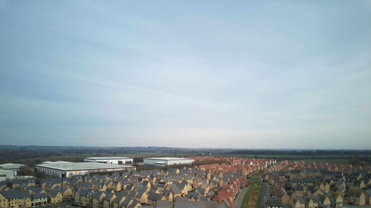 Aerial shots taken with the Veeniix V11PRO drone's camera showing houses and a skyline, roads with green surroundings and a multi-colored art display.