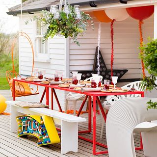 decking area with red rectangular table white benches and star lamp