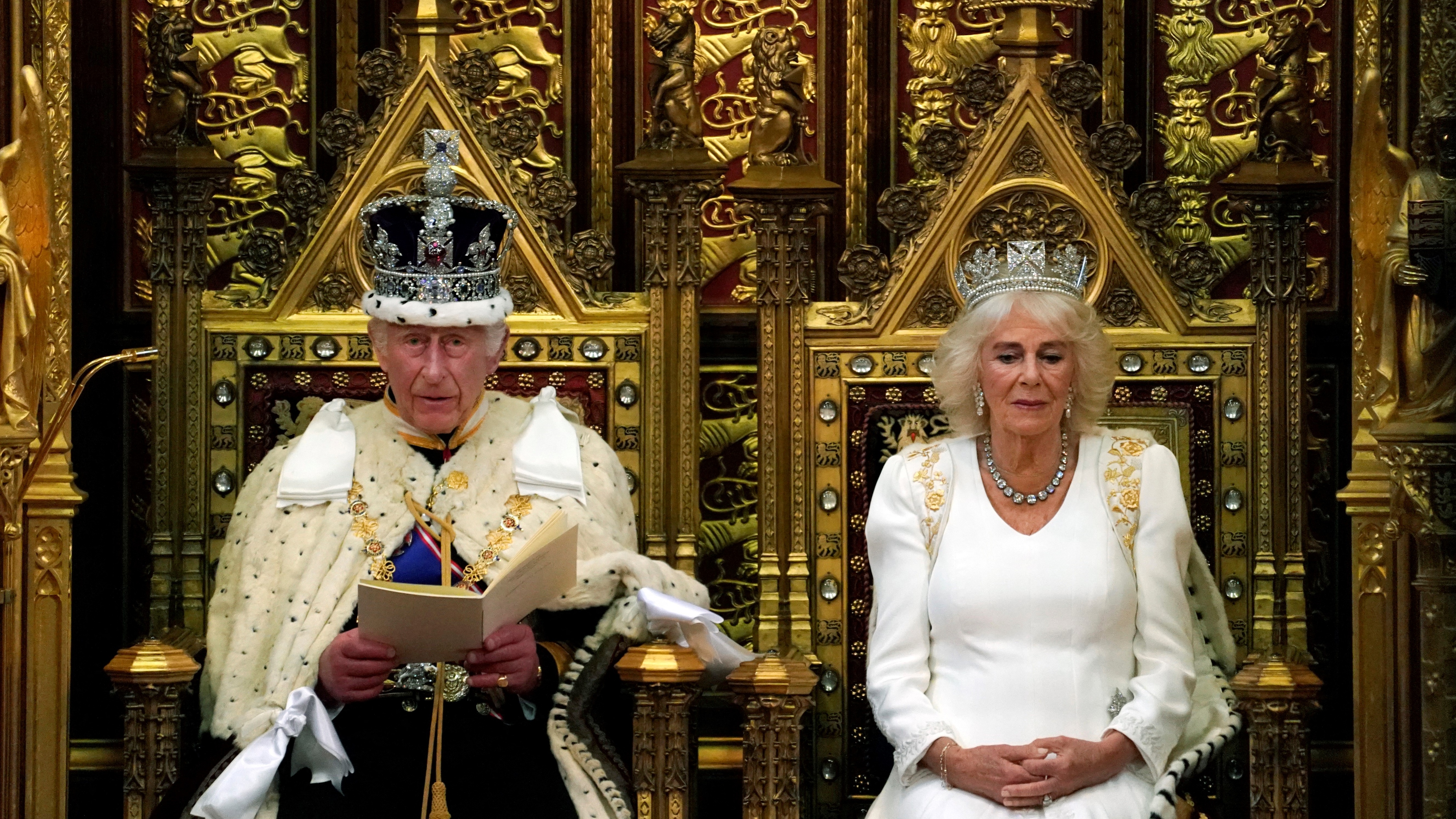 King Charles III, wearing the Imperial State Crown, sits alongside Queen Camilla, wearing the George IV State Diadem, as he reads the King's Speech during the State Opening of Parliament 2024
