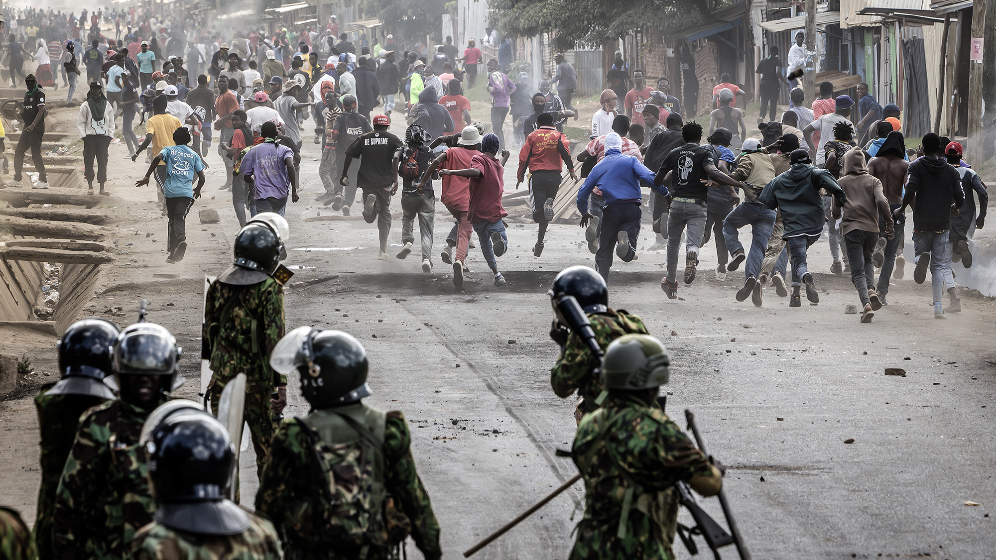 Protesters run for cover during a clash with police while demonstrating against a controversial Ebola quarantine center at Laikipia Air Base in Nanyuki, Kenya