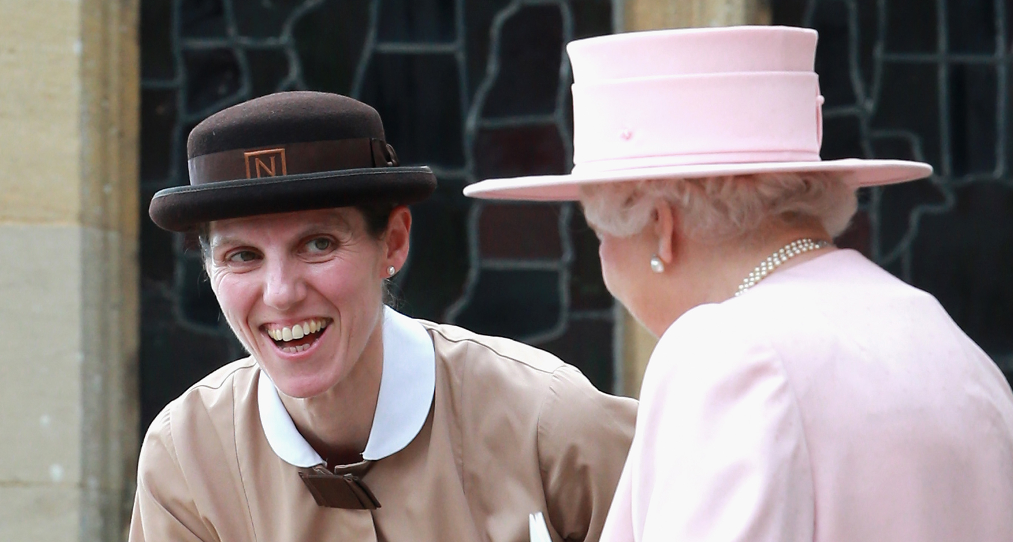 Nanny Maria smiling and talking to Queen Elizabeth, wearing a pink hat and coat