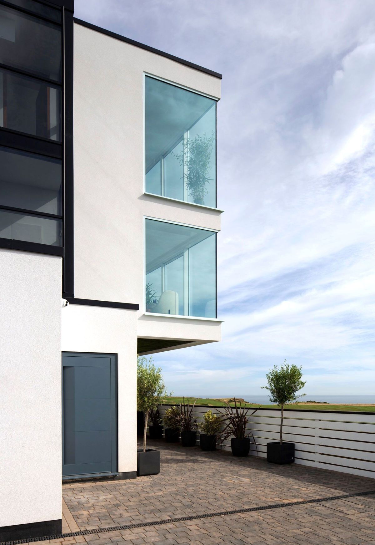 A white steel and glass box home on a coastal plot