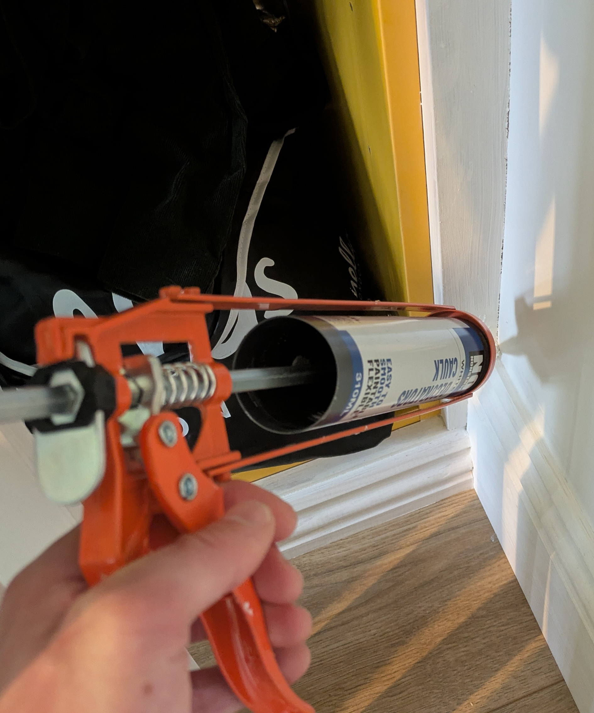 Caulking a skirting board using a skeleton gun