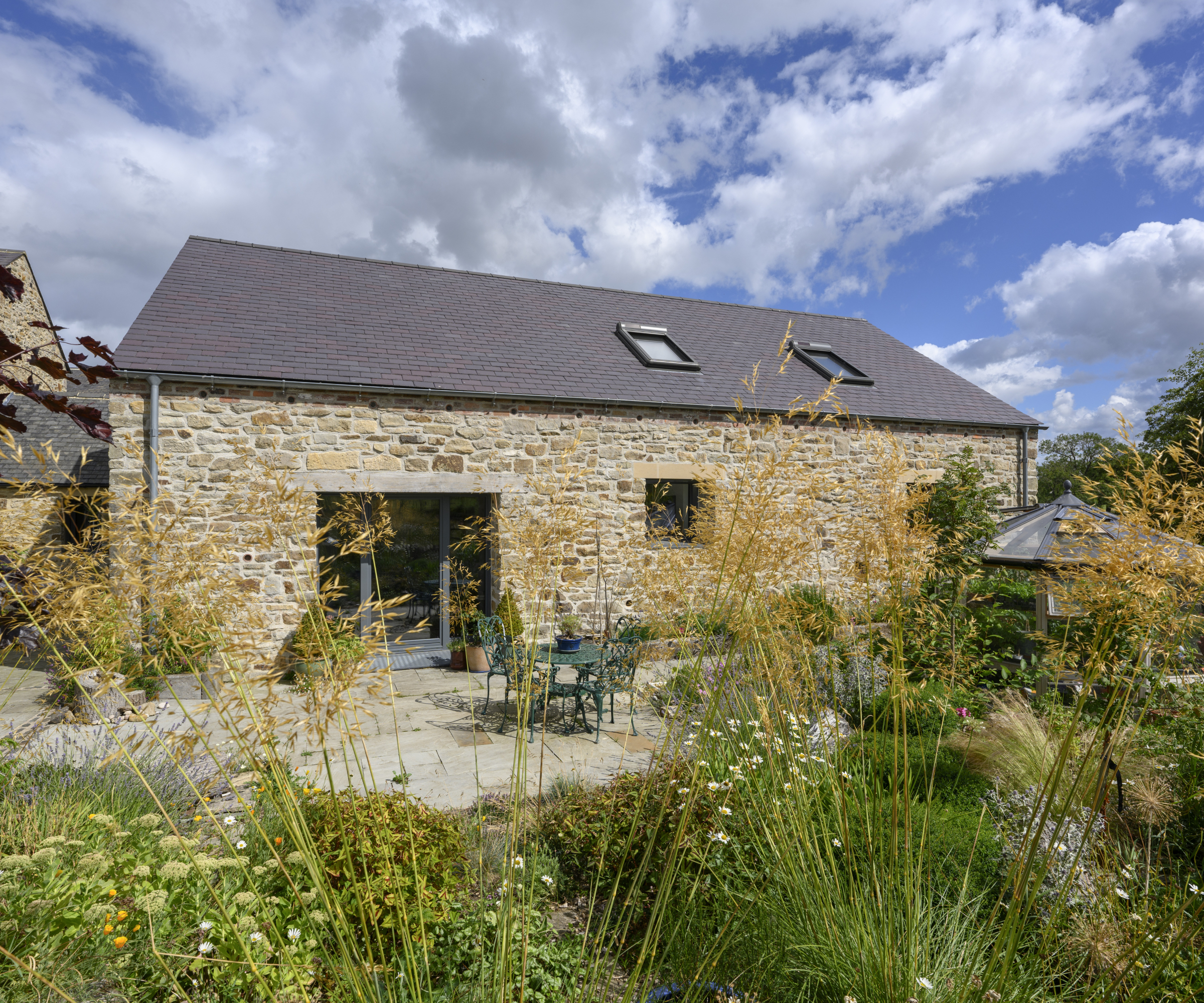 stone house with garden planted with tall grasses and shrubs