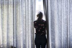 Woman looking out of the window in a dark room