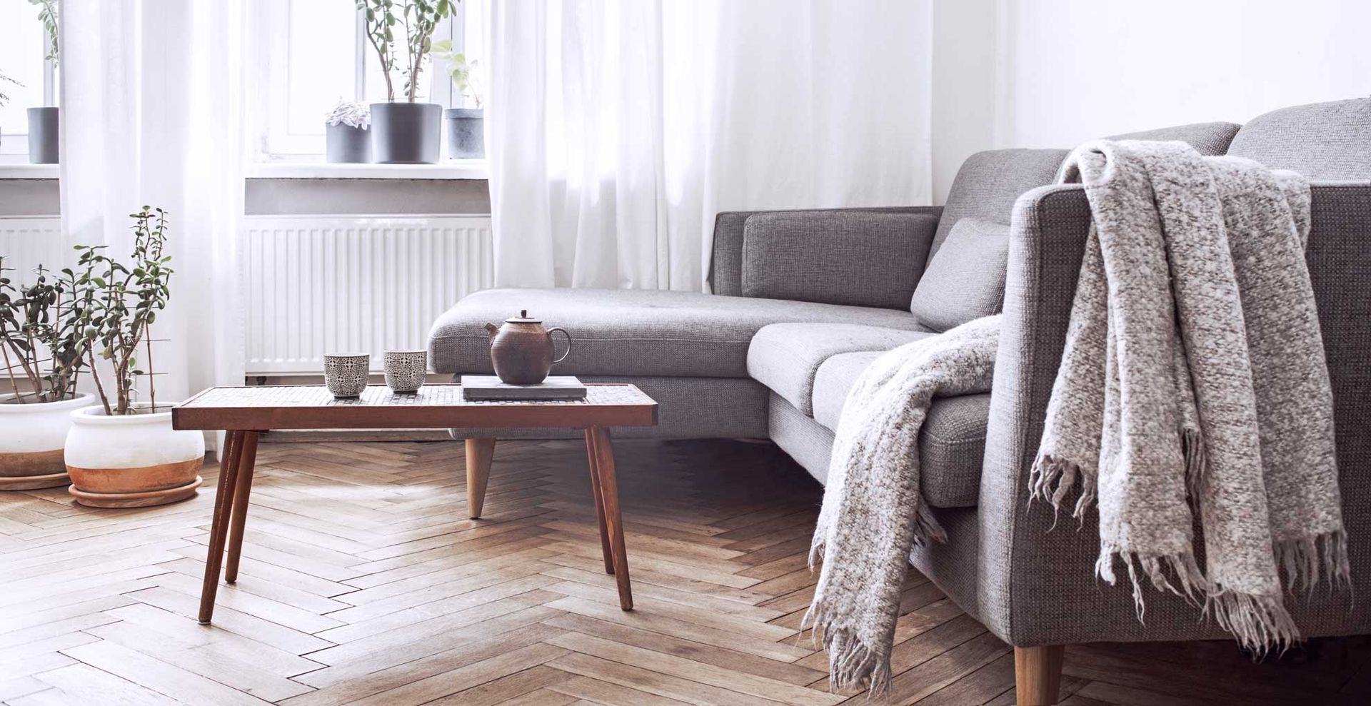 white and gray living room with gray couch and winter throw draped over teh edge to show what needs changing to transform the room on a budget